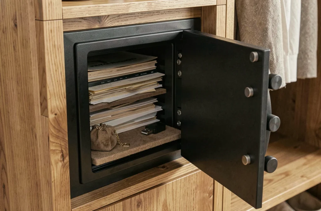 Coffre-fort encastré dans une armoire en bois avec documents et bijoux soigneusement rangés à l'intérieur