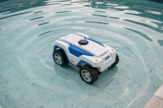 Robot nettoyeur de piscine autonome se déplaçant sur le fond d'un bassin extérieur aux eaux turquoise claires